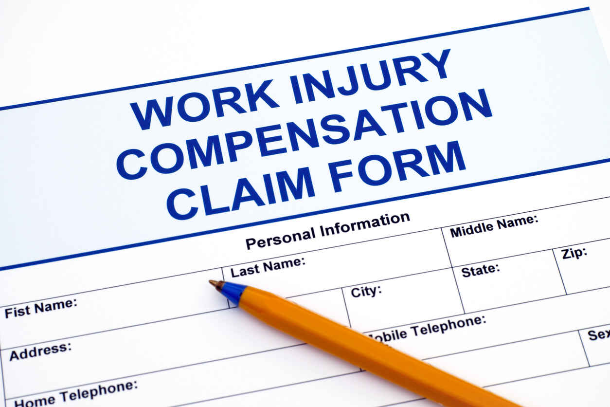 Workers' compensation claim form and a pen on a table, representing the legal process and documentation for work injury settlements.